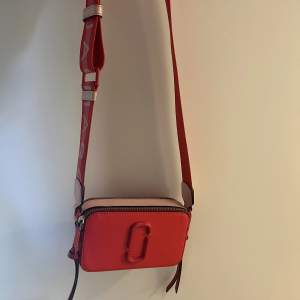 Säljer denna snygga Marc Jacobs väska❤️ väskan är röd med rosa detaljer.  är i hyfsat bra skick.  
