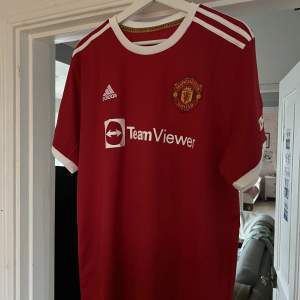 Manchester united matchtröja från säsongen 21/22 - helt oanvänd med tag kvar. - storlek XXL men passar mer som en XL skulle jag gissa - tröjan säljes eftersom den är för liten för mig som vanligtvis har XXL.  Tröjan har privat efternamn, därav priset.  