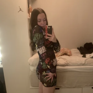 Graffiti klänning - En svart klänning med graffiti på som är lite genomskinlig, den är långärmad och väldigt skön 