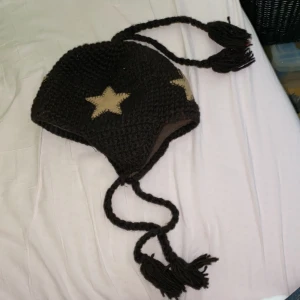 stickad mössa med stjärnmotiv - En stickad mössa med lappar för öronen och ”flätor” 