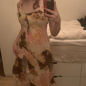 Hawaiian klänning - En jätte luftig medel lång klänning som går ner till mitten av vaderna, och som har hawaiian print i cream orange, brun och ljusrosa i olika prints.