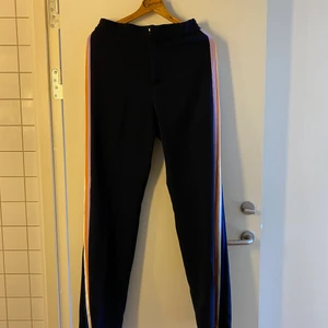 Kostymbyxor med färgglada ränder - Marinblå kostymbyxor med ränder på sidorna. Strl M