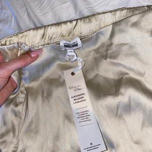 Satin kjol Bubbleroom X Alexandra Nilsson - Kjol från Alexandra Nilssons kollektion med Bubbleroom, köptes för 349 kr. Alla lappar sitter kvar, helt oanvänd 🤍  Färgen är en fin champagne-färg, syns bäst på första bilden. 🤍  Kjolen har en ”slit” på ena benet och det finns resår runt midjan 🤍