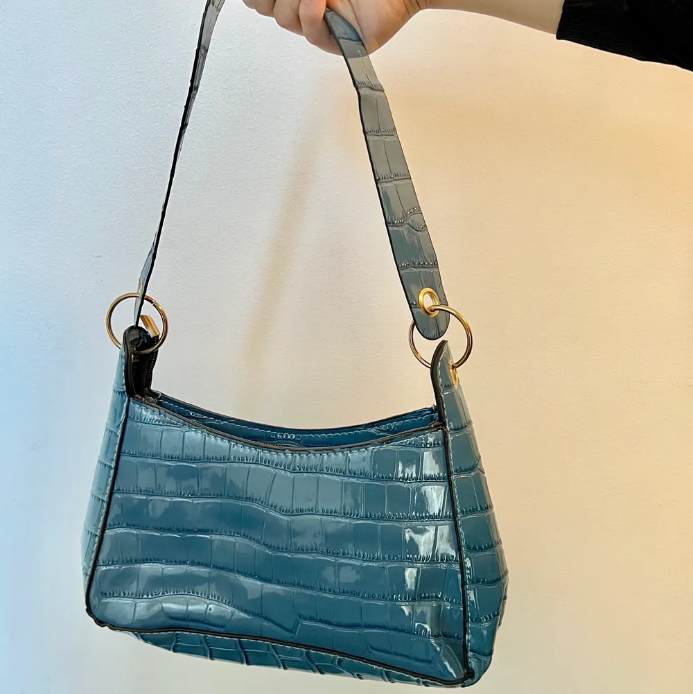 Säljer en söt blå väska!  Väskan är i mörkblå färg med ett glansigt matrial. Säljs pågrund av att jag har för mycket väskor. Köparen står för frakten  (Första bilden visar bäst ljus) . Accessoarer.