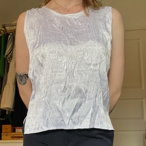 Vitt linne med skimrande mönster  - Coolt vitt linne med ett skimmrqnde vävt mönster. Etiketten är storlekslös men sitter som M.  Du som köper står för frakt, möts annars upp vid Stockholm city.