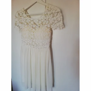 Vit spetsklänning, strl S - Använd endast vid studenten, strl S, med vadering vid kuporna samt spets upp till, två tyger nertill en silkes och en tjockare baktill. Går lite ovanför knäna för en som är ca 1.60 lång