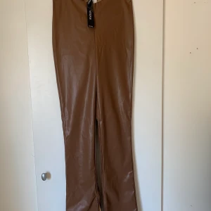 Oanvända fejk läderbyxor  - Så snygga bruna fejk läderbyxor från hm, med en slits längst ner. Oanvända
