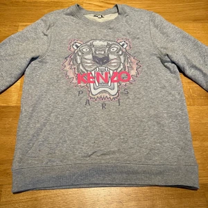 Kenzo sweatshirt  - Säljer den här väldigt fina Kenzo sweatshirten, självklart äkta, har tyvärr inte kvitto. Den är i ljus grå med rosa och vitt tryck. Sweatshirten är använd ett fåtal gånger och är i nyskick. Det är en barnstorlek i 14 år. 