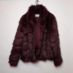 Pälsjacka - Jättefin pälskappa som är lite mörkröd/mörklila, knappt använd så är fortfarande väldigt fin i hela pälsen (fejkpäls) storlek 36 men skulle säga den passar från S-M även L beroende på vilken passform man söker 