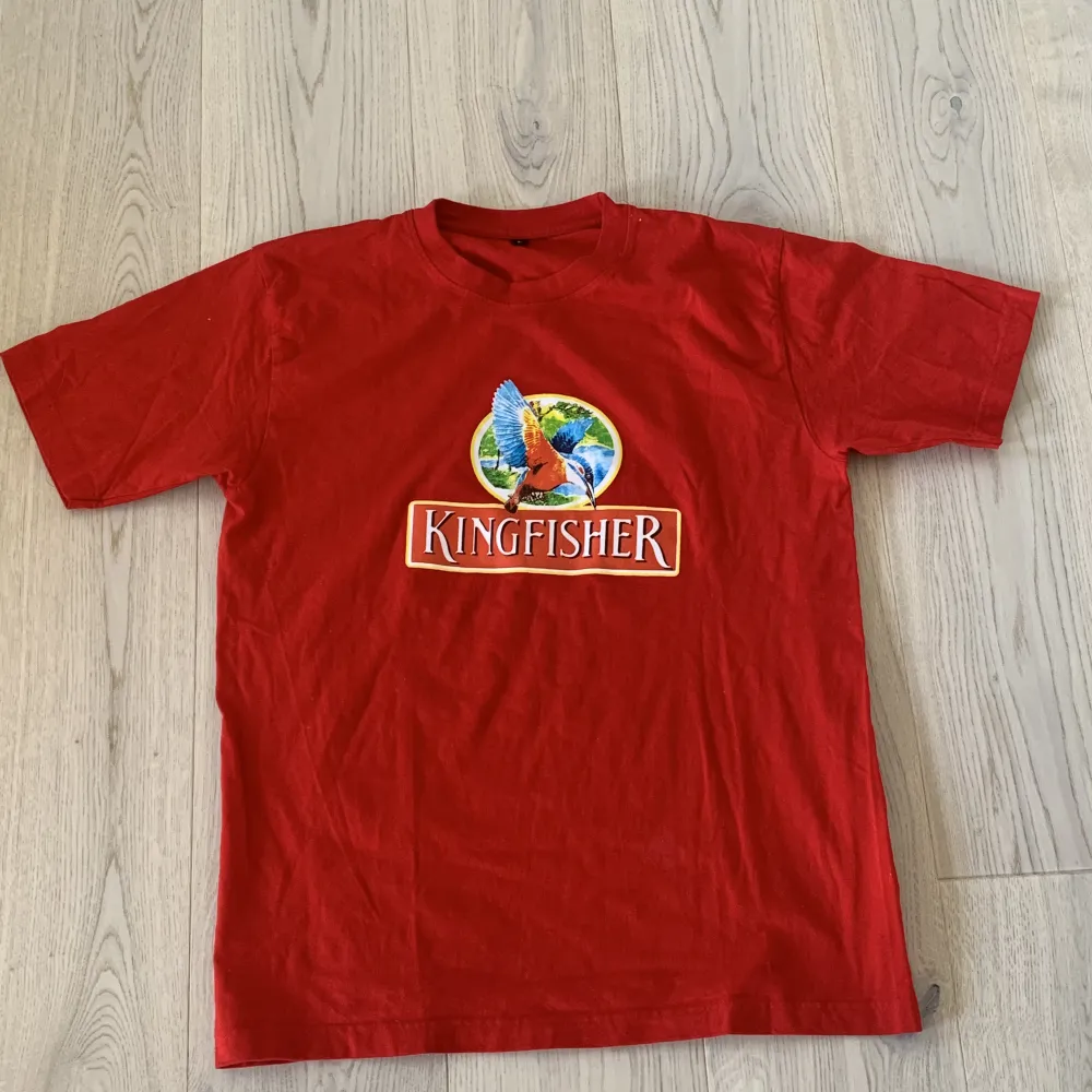 Röd tshirt med ölmärket kingfisher. Skick 9/10  Trycket är perfekt och inte crackat SIZE: L Inga fläckar eller liknande. Köpare betalar frakt.  Köpare betalar frakt. T-shirts.