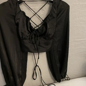 Svart topp - Svart topp från Nelly. Knytning i ryggen. Använd 1 gång