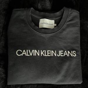Svart collegetröja från Calvin Klein Jeans i storlek S. Tröjan är använd ett par gånger och är i väldigt fint skick. 