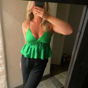 Grönt linne  - Säljer grönt linne med volanger, tyvärr kommer de inte till användning och säljs därför, TOPPEN FINNS KVAR