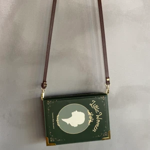 Charmig ”bok” axelväska - En superfin axelväska som ska föreställa ett bokomslag. Köpt från etsy, ganska liten i storleken (får plats med mobil/plånbok). Går att byta ut axelbandet. Knappt använd och bra skick!