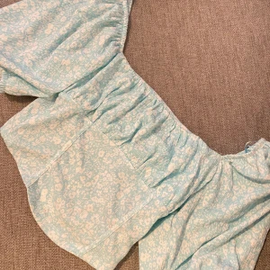 Tröja  - Världens finaste sommar topp!🌸 Super fin ljus turkos färg med vita blommor🌸 Storlek M. Aldrig använd. Köpte från Ginatricot för några veckor sedan💓 Säljer för 100kr plus frakt 