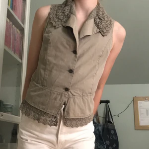 Cottagecore väst - En brungrå väst/blus som påminner om cottagecore, stl M från märket Noa Noa. Den är köpt secondhand men aldrig använts då den inte passar min stil. Det finns inga defekter, och alla fina detaljer är intakt 🌼