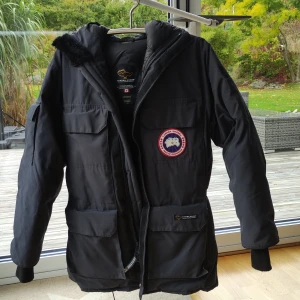 Canada Goose - Coyote  - En mycket sparsamt använd Canada Goose jacka i mycket fint skick söker ny ägare. Sömmar är fina, fullt fungerande och hela kardborreband och dragkedja. Huva med äkta päls som i nyskick.  Sitter bra på mig som normalt använder Medium storlekar