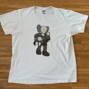 Kaws x uniqlo - Uniqlo x kaws collab tee storlek XL Sold out för länge sedan Inga fel förutom lite skrynklig och ett jättelitet knappt synligt hål i fram.