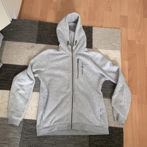 SAIL RACING GRÅ JR BOWMAN ZIP HOOD - Sailracing zip hoodie i grå färg, mycket fint skick, knappast använd. (Nypris: 999kr)