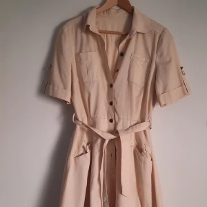 Vintage klänning - Vintage klänning. Ingen storlek utskriven men passar 36/38. Saknas knappar vid fickorna, annars mycket fint skick. Färg beige