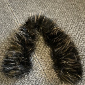 Pälskrage  - Pälskrage med fake päls. Pälsen är svart med brunt i. Pälsen är från rock and blue.  Passar rock and blue jackor vad jag vet, då den satt på en sådan innan. Passar säkert fler jackor. Pälsen sätts fast med knapar.