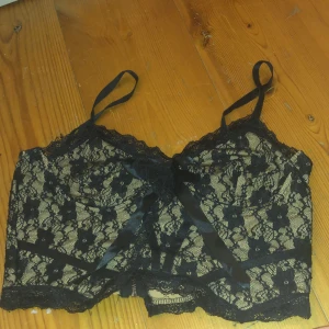 Spets Topp - Beige och svart spets topp med rosett. Har dragkedja och är aldrig använt. 