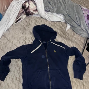 Ralph lauren zip hoodie - Polo Ralph lauren hoodie i fint skick, dragkedjan är lite sönder uppe vid snöret men går gangska snabbt och smidigt att sätta tillbaka blixtlåset tillbaka på rälsen annars är tröjan i väldigt bra skick och säljs pga för liten storlek. Köpt för nypris 1400