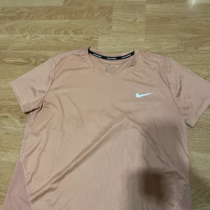 Tränings t-shirt - Säljer denna då den aldrig kommit till användning utan bara legat i garderoben, den är i strl m men borde passa en L oxå. Tröjan är i rosa beige färg. 