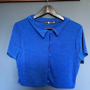 Kornblå topp - Kornblå top med knäppning i super skönt ”sladdrigt” material. Croppad modell passar allt imellan S-L