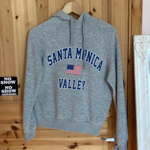 Grå hoodie  - En grå hoodie med tryck i fint skick från Gina. Säljs för den används Inte. 