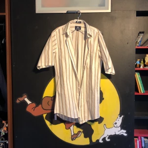 Lång skjorta - Lång, randig, bekväm skjorta/skjortklänning. Passar mig som är 178 cm lång som en längre skjorta/tunika. Otroligt bekväm och skrynklar aldrig. 