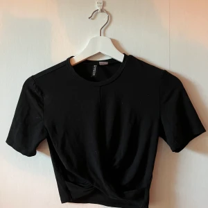 Svart croppad topp - Svart croppad topp i fint skick som är ”tvinnad” nedtill!
