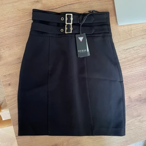 Kjol från Guess - Svart pennkjol från guess med prislappen kvar (alltså aldrig använd). Guldiga detaljer framtill, dragkedja baktill.