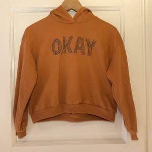 Terrakotta-färgad hoodie från Lindex Kort modell (24 cm mätt från armhålan) Saknas 2 ”metallpärlor” i ordet OKAY, se bild. I övrigt mycket fint skick. 