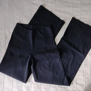 Svarta stretchiga vida byxor, storlek XS - Vida svarta byxor med stretch. Medelhög midja med sydda "pressveck" båda i fram och i bak - sitter därför skitsnyggt. Dragkedja i sidan. Något urtvättade och slitna i nederkant. Tyvärr inte steamade. 72% viskos, 22% polyamid och 6% elastan. Storlek XS.