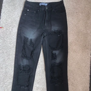 Svarta slitna jeans strl 36 - Svarta jeans men hål över hela benen och uppvikta kanter. Väldigt coola jeans men tyvärr blev dom för små. Endast använda 2 gånger. Skulle säga att den passar 34-36