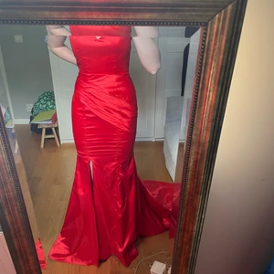 Röd balklänning med öppen rygg  - Säljer min fina balklänning då jag bestämde mig för att behålla en annan:) Klänningen är i XXS i satinmaterial, den är öppen i ryggen och har släp. Ett litet hål i innertyget vid rumpan, men inget som syns eller märks! Köpt på Hebeos. Skriv privat för fler bilder! 