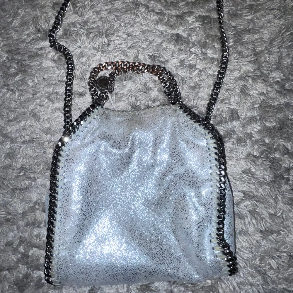  Säljer min ljusblå/grå glittriga Stella McCartney väska, självklart äkta. minsta stoleken. Så snygg och lite unikare då den är glittrig. Den har tappat lite färg på handtagen men inget som märks. Nypris ca 7500 kr. . Väskor.