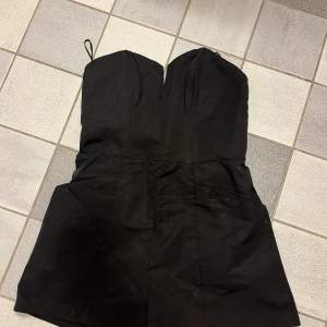 En helt ny, jättesnygg jumpsuit i svart. Fickor på sidorna och dragkedja längs ryggen. Stl 36 