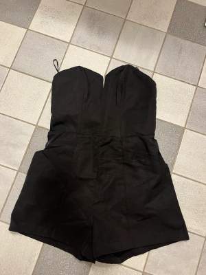 En helt ny, jättesnygg jumpsuit i svart. Fickor på sidorna och dragkedja längs ryggen. Stl 36 