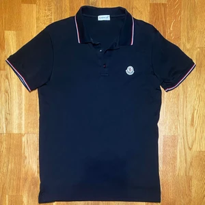 Moncler Piké  - En svart Moncler Piké i storlek M köpt 2022 på Moncler i London. Säljs pga att den inte används. Skick 10/10, nästan aldrig använd. Nypris på 2499 kr. Köpare står för eventuell frakt. Bara att höra av dig om du har några frågor!