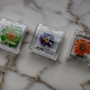 Jane Hellen - tre ögonskuggor/highlighters - Flower smink 🌸 - Jane Hellen Flower eyeshadow/highlighters med riktiga blommor i locken. Har blivit liggande länge utan att komma till användning - de är bara testade. Tre olika nyanser. 4 g i varje burk. 