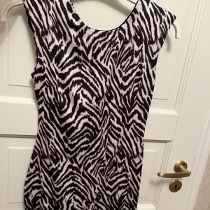 Snygg festklänning  - Jättesnygg festklänning med axelvaddar och djupare rygg! I glansigt stretch tyg! Aldrig använd 