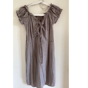 Grå mönstrad klänning med snöre - Grå klänning bra skick, liten i storlek. Rekommenderar utan BH annars för tight. Välanvänd. Bra skick. 