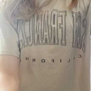 Oversized tshisrt  - Säljer denna beiga tröjan med text köpt förra året men andvönd fåtal ggr💗 är i XS men den är oversized så passar även S-M💗