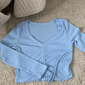 Tröja med snöre storlek S - Ljusblå tröja med snöre som man drar åt för att justera hur kort/lång den ska vara. Köpt från shein men aldrig använd pga inte min stil. Som ny