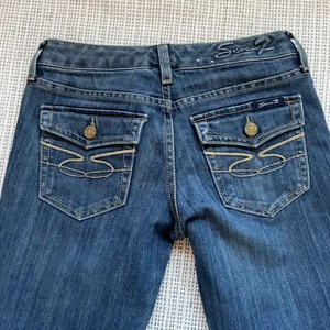 Lågmidjade bootcut jeans  - Säljer ett par bootcut jeans med fickor på rumpan, ser ut som true religion jeans men är från märket seven7. Storlek 25 i midjan och passar mig som är 167cm lång. ☺️  Midjemått: ca 70cm innerbenslängd: ca 80cm                                         