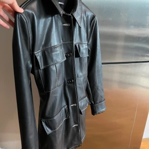 Läderkappa strl S - Säljer min superfina kappa i skinnimitation från Gina Tricot i strl S då den inte kommit till användning. Nypris ca 900kr. Varan är knappt använd dvs som i nytt skick.  Säljer direkt för 300kr. Köparen står för frakt.