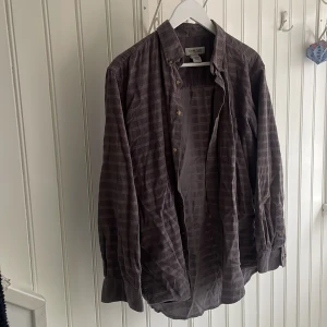 Oversized skjorta - En superfin mörklila/grå skjorta i ett tjockare material som jag haft så mycket användning av. Köpt second hand i Stockholm. Längre modell som går över rumpan. Kan även användas som ”jacka” på sommaren. Strl M, men oversized.