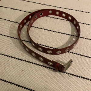 Vinröd bälte - Bälte från PrettyLittleThings, några år gammalt men endast använt 1-2 ggr. Vinröd och läderimitation. Storlek har jag ej men bältet är ca 135 cm lång, bredd är 3,5 cm.